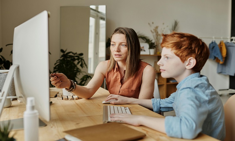 Mother teaching son about money using a computer.