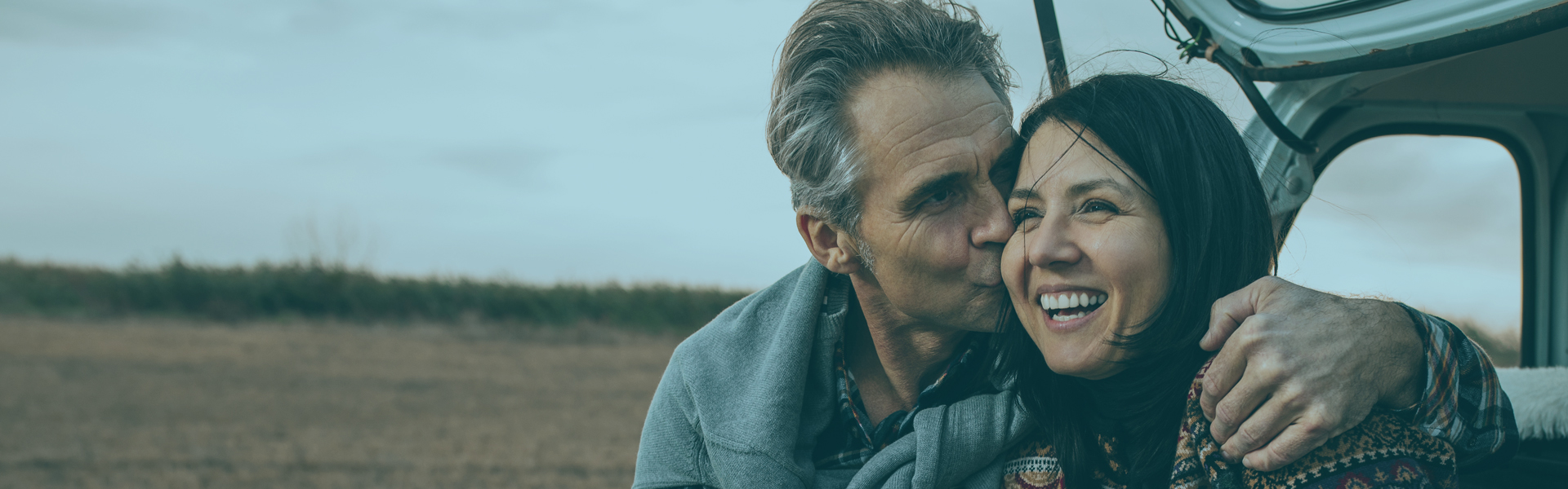 Couple sitting on edge of the trunk of their car | Loan Rates Hero