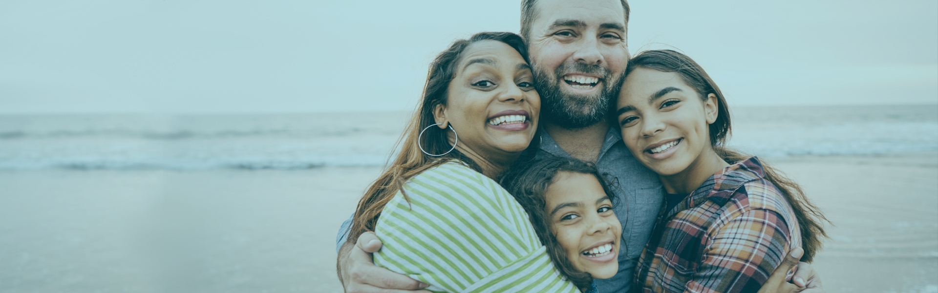 Family hugging on beach | Member Services